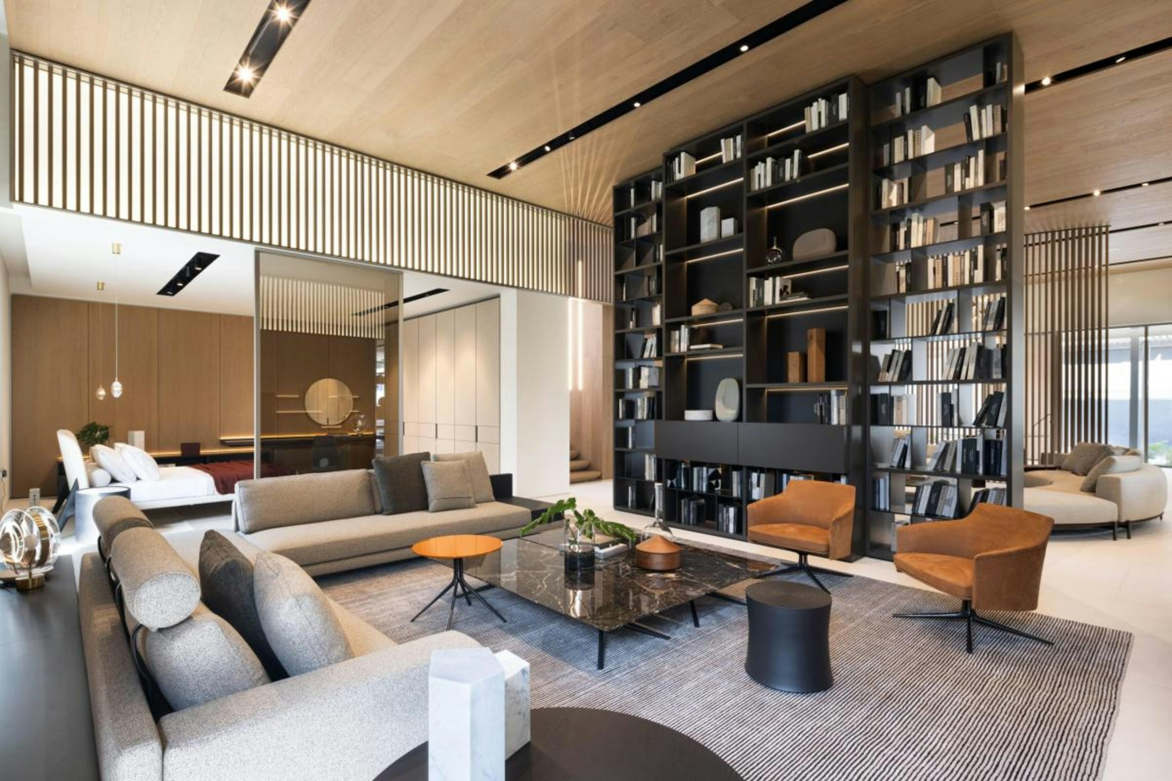Furnished apartment living room with a floor-to-ceiling bookshelf arranged by color